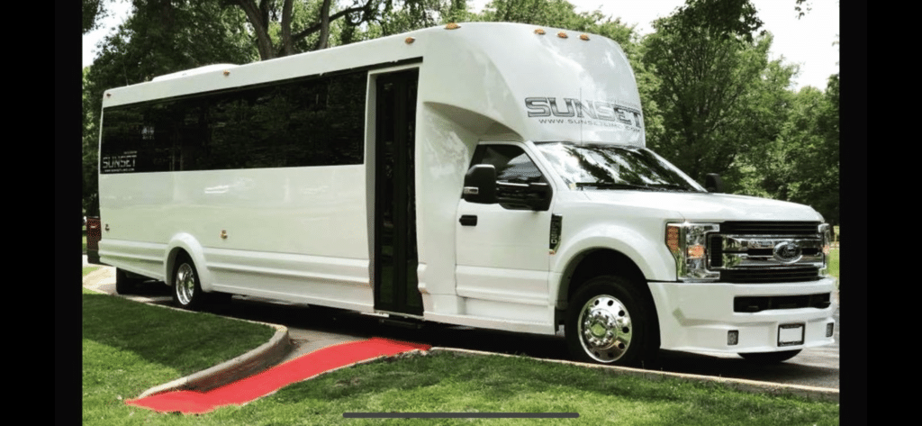 A white party bus with the door open ready and a red carpet laid out in front of it