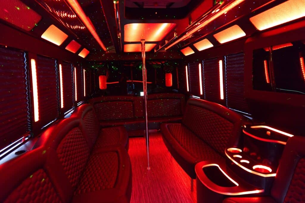 Interior of the 20 passenger limo with red lighting, seats, ice and water, and a pole.