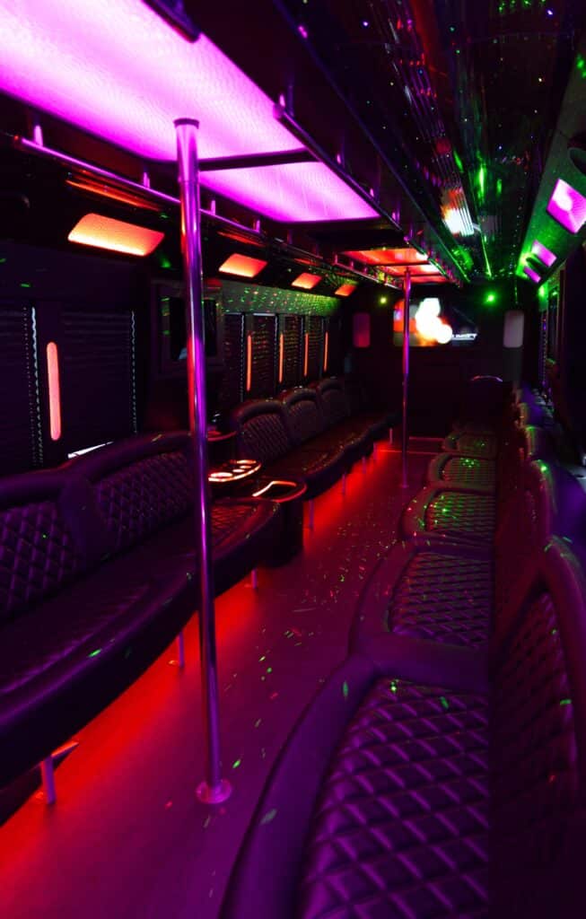 Limo bus 46-50 passenger. Inside with seats, tvs, lights, and poles.