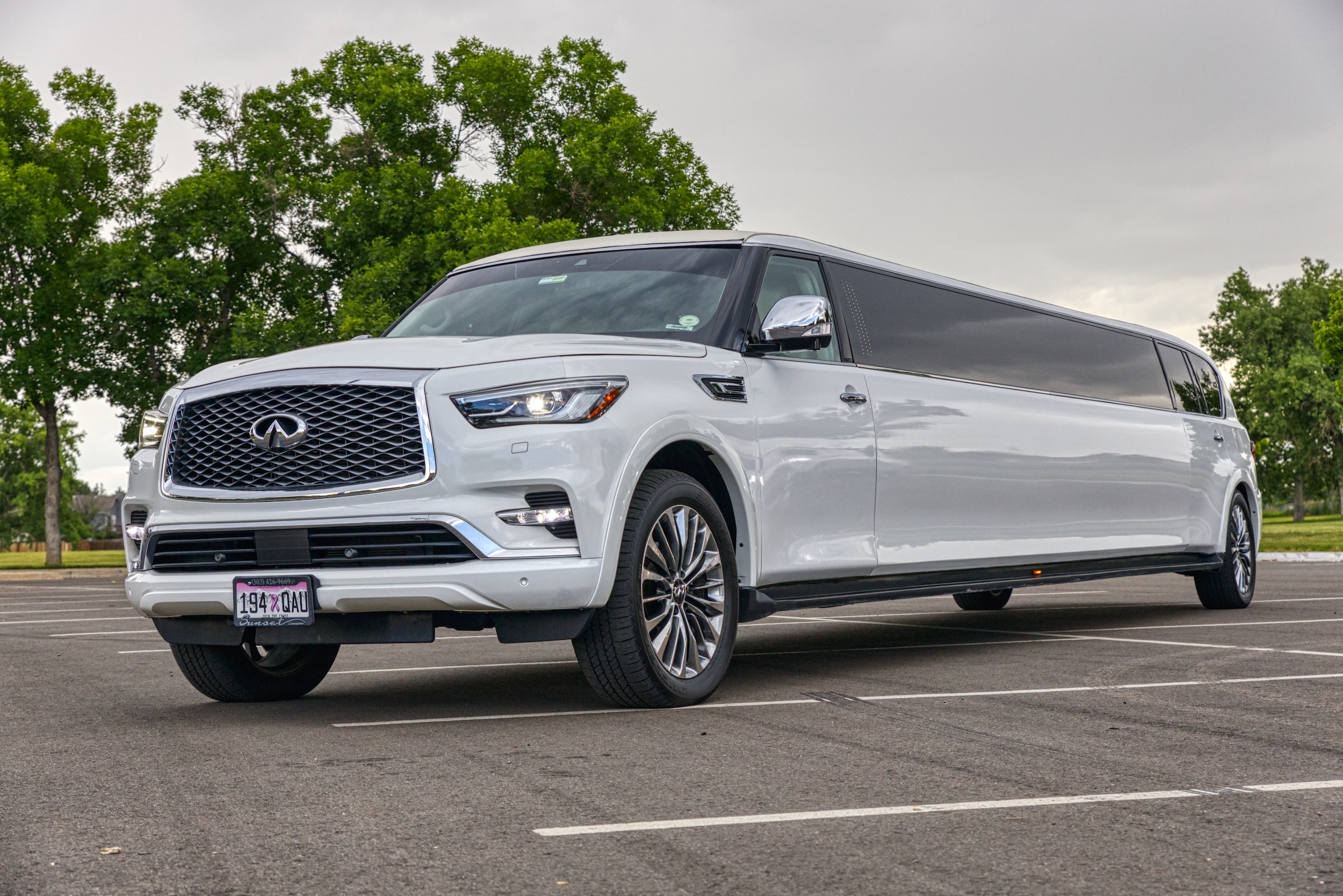 A white Infiniti Qx80 with a gull-wing door open