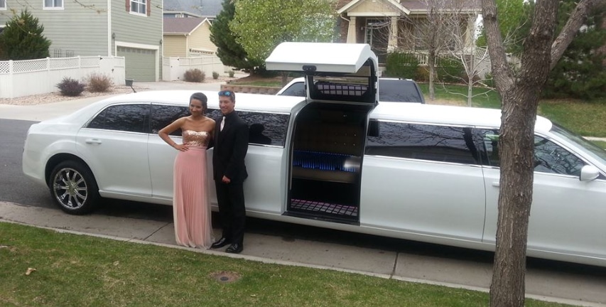 A black limo with the red carpet laid out. People ready to go to prom.